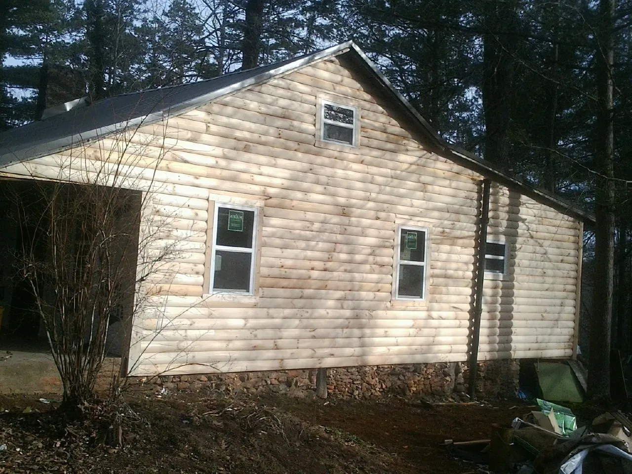New log siding and dark metal roofing on a gable end in Delano