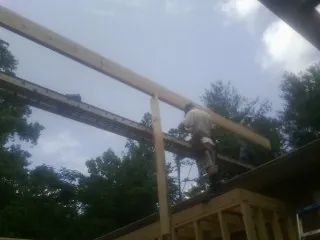 Carpenter setting a ridge beam over a new addition frame — Ice Dam Removal by Roofing Brothers in Delano