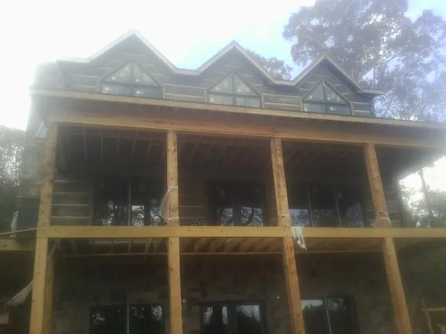 Dormers and porch framing on a large log home under construction — Roof Coating work by our crew in Delano