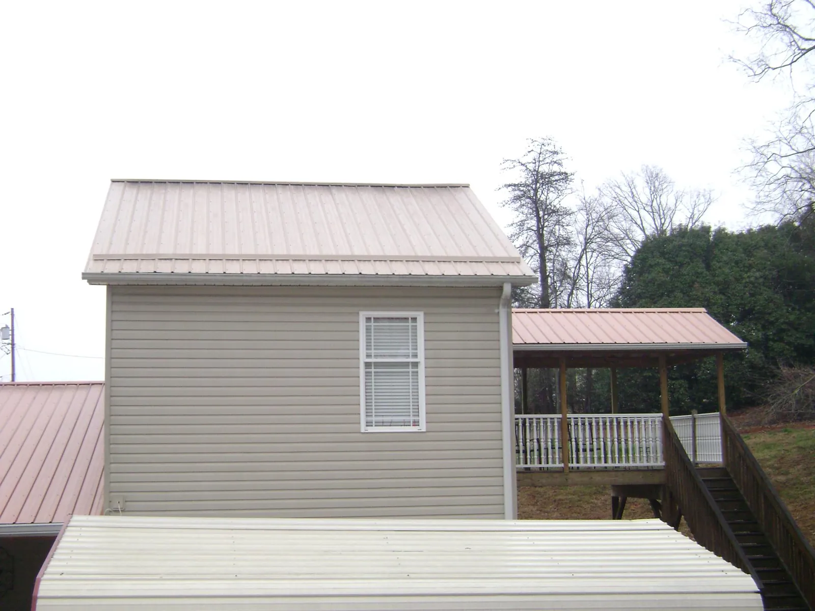 Tan metal roofs on a two story addition and attached porch, from a Roof Replacement job in Delano