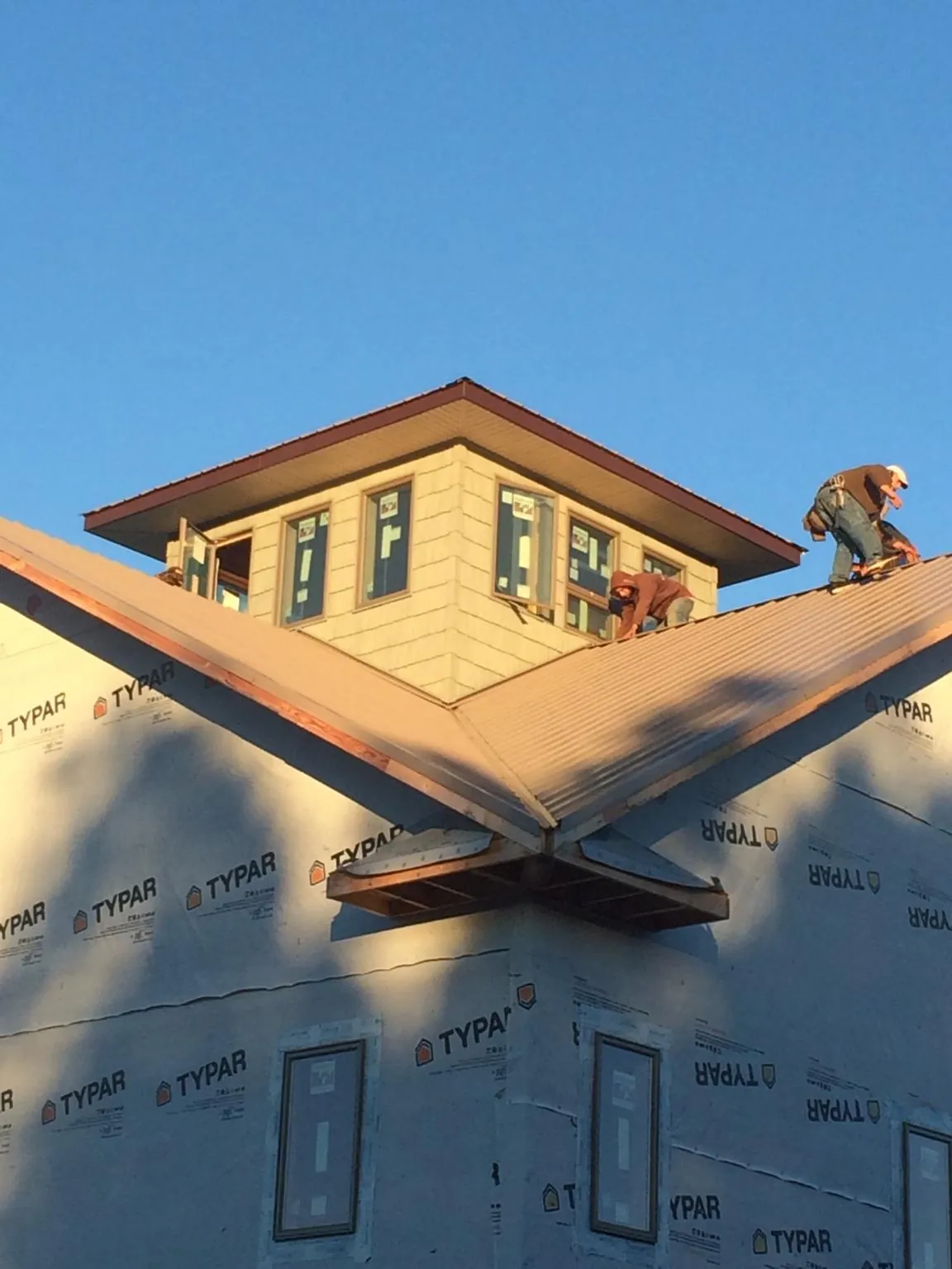 Roofers working around a rooftop cupola on a new metal roof at sunset — Roof Waterproofing in Delano by Roofing Brothers